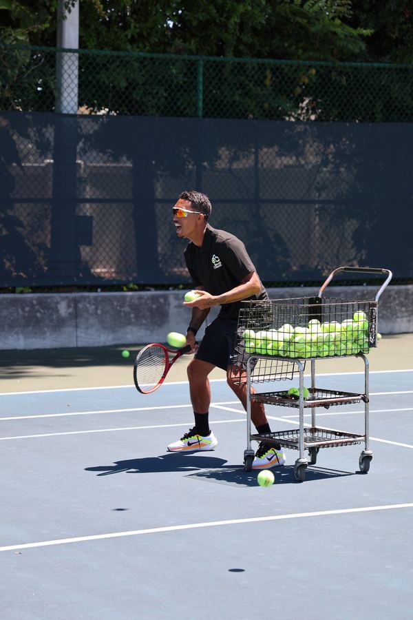 Coach Liam feeding balls from the cart during a clinic